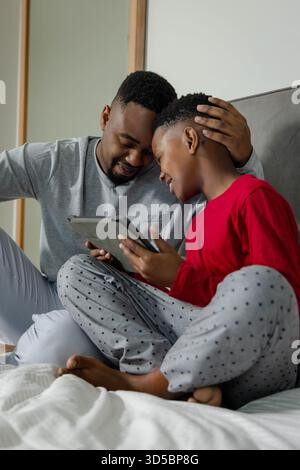 African American father and son bonding at home, smiling while using digital tablet together Stock Photo