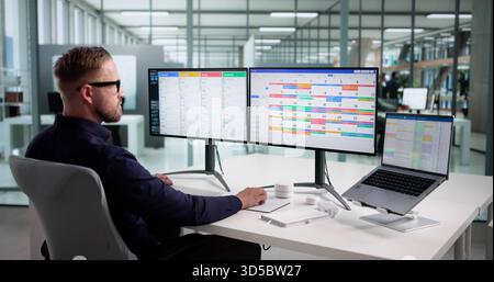 Efficient Caucasian Male Developer Manages Scrum Calendar On Multiple Screens Stock Photo