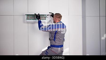 Male AC Technician Installing Air Conditioner For Cold Indoor Environment. Stock Photo