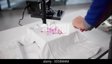 Man Creating Custom T-shirt Designs At Heat Press Printing Workshop. Stock Photo