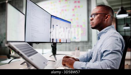 Man Coding Ecommerce Software On Multiple Monitors In Office Chair Stock Photo