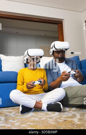 Father and son enjoying virtual reality gaming together on living room floor Stock Photo