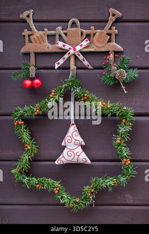 christmas star made of yew branches and rose hips and fabric christmas tree hanging on the wall Stock Photo