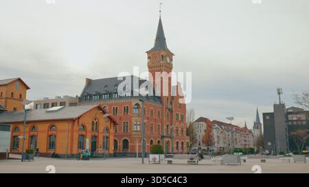 City square features a charming historic clock tower and colorful buildings under a gray sky in the afternoon. Stock Photo