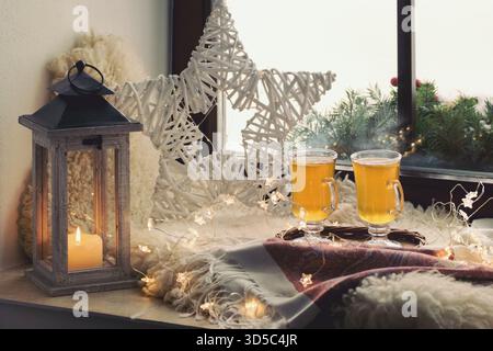 Christmas still life - lantern, star, lights and two cups of hot tea on the window Stock Photo