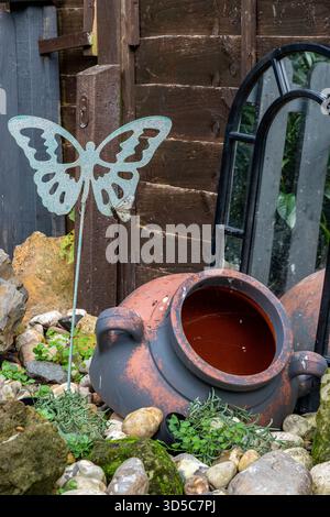 Decorative garden items including mirror, Butterfly and terracotta earthenware pot or Greek urn. Stock Photo