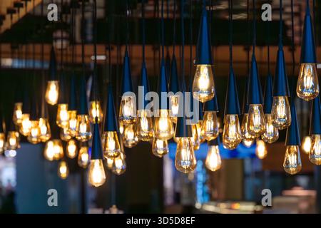 Lots of decorative soft light bulbs hanging from the ceiling in a dark room Stock Photo