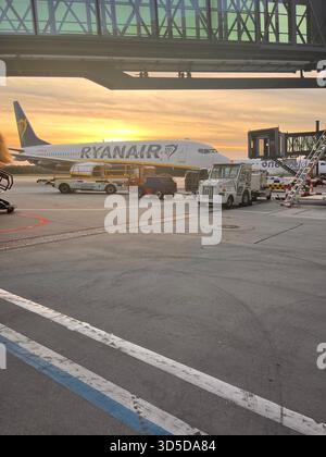 Ryanair passenger airplane parked on the apron during sunset at Leeds Bradford Airport, England, with ground service vehicles. Stock Photo