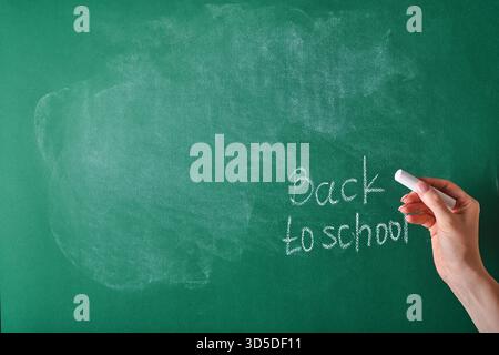 Female teachers hand writing on school board back to school white chalk. Concept back to school. Mock up for design. Copy space. Education Concept. Stock Photo