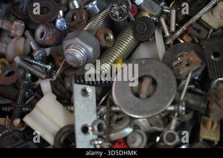 A close-up, high-angle shot of a diverse assortment of metal and plastic fasteners, including nuts, bolts, washers, and springs Stock Photo