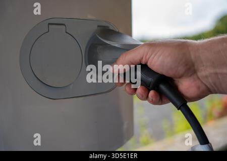 Close-up of hands connecting cables to an electric vehicle charger Stock Photo