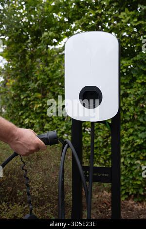 Close-up of hands connecting cables to an electric vehicle charger Stock Photo