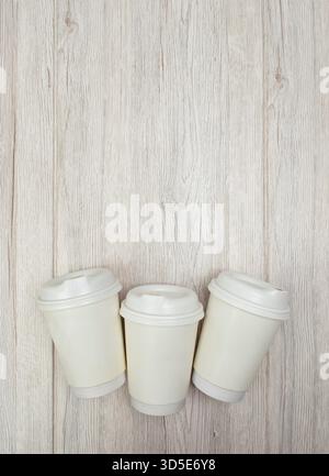 Eco paper coffee cups arranged on a light wood background, shown from above in a flat lay composition Stock Photo
