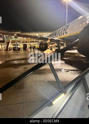 Nighttime view of a Ryanair airplane parked on a wet tarmac at Leeds Bradford Airport Stock Photo