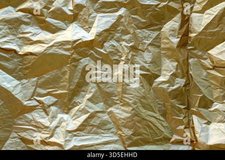 Crinkled gold foil texture as an abstract background with luminous metallic shine Stock Photo