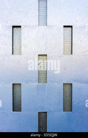 Blue Textured Wall With Vertical Glass Windows Creating Modern Geometric Pattern Stock Photo