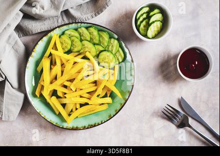 Appetizing French fries and cucumber slices on a plate on the table top view Stock Photo