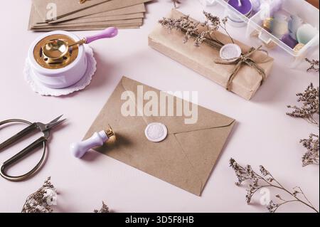 Craft envelope with wax seal and crafting items on pink Stock Photo
