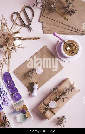 Craft envelope with wax seal and crafting items on pink top and vertical view Stock Photo