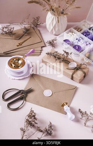 Craft envelope with wax seal and crafting items on pink vertical view Stock Photo
