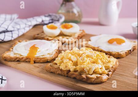 Scrambled egg, poached egg, fried egg, boiled egg on toast on a board Stock Photo