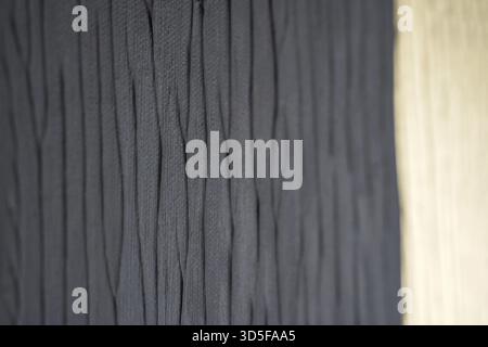 Close up of textured dark fabric with wavy pattern next to wooden surface Stock Photo