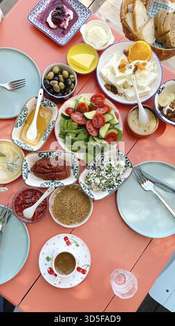 Traditional Turkish breakfast served on a colorful table with various cheeses, vegetables, olives, jams, honey, bread and coffee, vertical, concept of Stock Photo