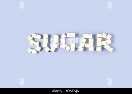 Arrangement of white sugar cubes forming the word 'sugar' on light blue background Stock Photo