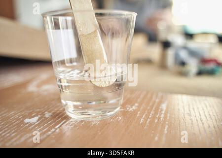Clear plastic cup with stir stick on wooden surface in well lit room Stock Photo