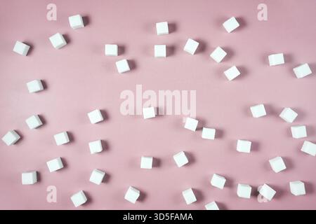 White sugar cubes scattered on pink background in random pattern Stock Photo