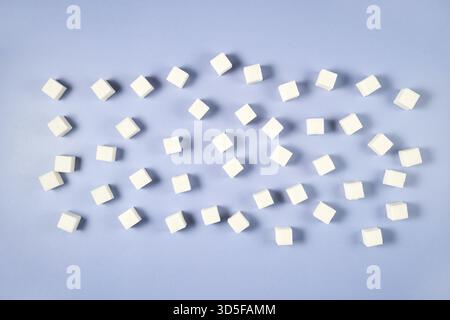 Scattered white sugar cubes on light blue background for sweetness concept Stock Photo