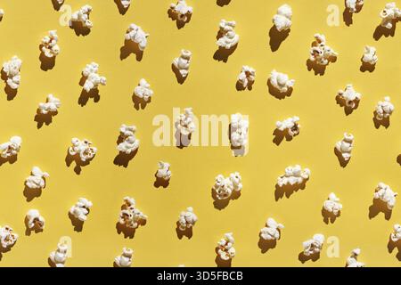 White popcorn design. Creative wallpaper. Yellow bright background. Cinema food concept. Film delicious snack. Many different pieces. Trendy pattern. Stock Photo