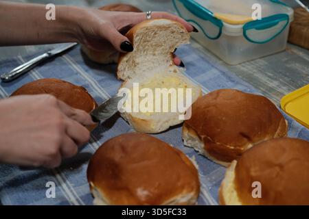 Spreading Butter on Fresh Bread Rolls in the Kitchen Stock Photo