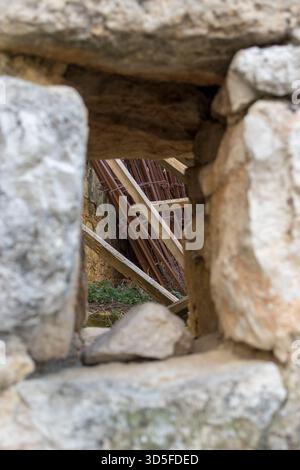 View through a window on a stone wall in an old stone building. View of ironwork and construction materials Stock Photo