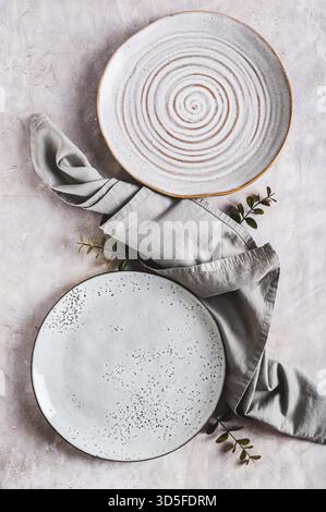 Pair of empty ceramic plates with napkin on gray background top and vertical view Stock Photo