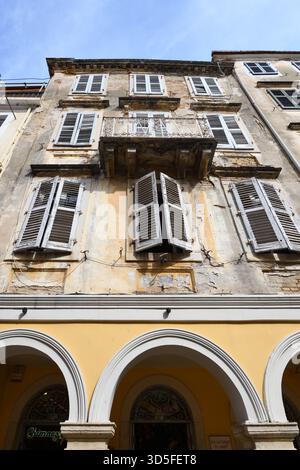 Shuttered windows on a building falling into disrepair adding to the character of Corfu Old Town, Greece Stock Photo