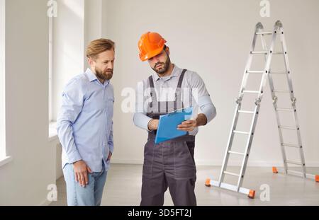 Man homeowner standing with foreman in new apartment discussing contract for construction work. Stock Photo