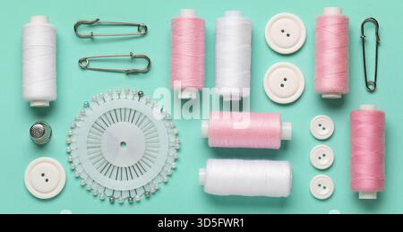 Thread spools, pins and buttons on turquoise background Stock Photo