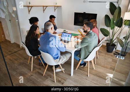 Business team meeting around table reviewing project charts Stock Photo