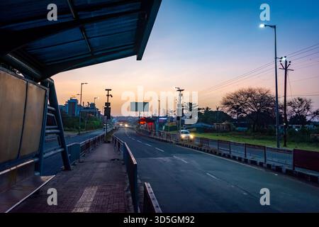 BHOPAL, MADHYA PRADESH, INDIA - DECEMBER 04, 2021: Empty city road and bus stop shelter at dusk with streetlights illuminating the horizon and traffic Stock Photo