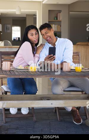 Couple making funny faces taking selfie at breakfast table with orange juice Stock Photo