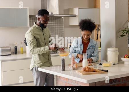 Preparing breakfast in modern kitchen, African American couple smiling together Stock Photo