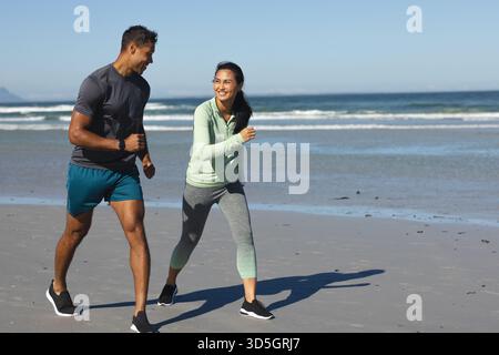 Couple jogging on beach, smiling and enjoying morning exercise together Stock Photo