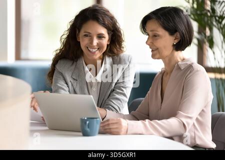 Young mature female professionals collaborating at notebook in friendly partnership Stock Photo