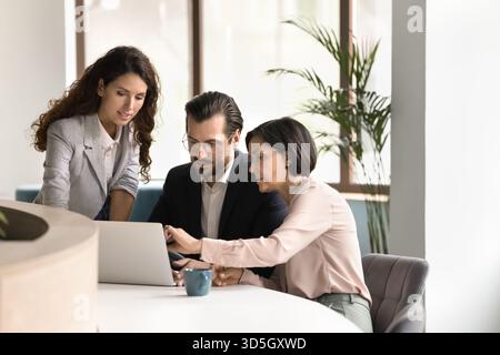 Three diverse business professionals work together on project using notebook Stock Photo