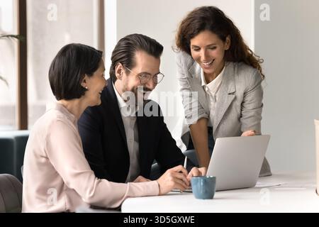 Happy diverse business team reviewing successful result on laptop screen Stock Photo