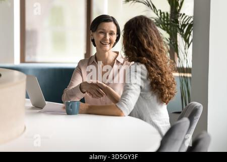 Smiling female client shake hands with insurance agent making agreement Stock Photo
