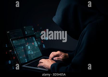Cybersecurity hacker in dark hoodie with laptop and virtual data. Cybercrime concept of illegal anonymous internet criminal activity and privacy breac Stock Photo