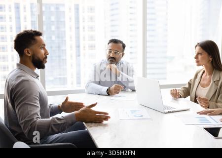 Diverse team of different aged coworkers talking at negotiation table Stock Photo