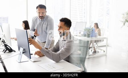 Serious busy diverse young and senior coworkers discussing Internet content Stock Photo
